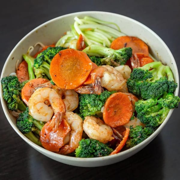A bowl of Vietnamese stir-fried shrimp with broccoli, carrots, and other vegetables.