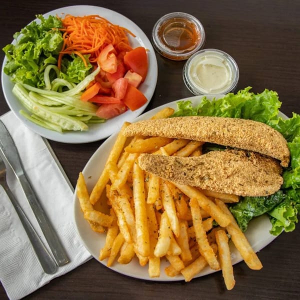 Crispy fish fillets with french fries and a side salad of lettuce, carrots, cucumbers, and tomatoes.